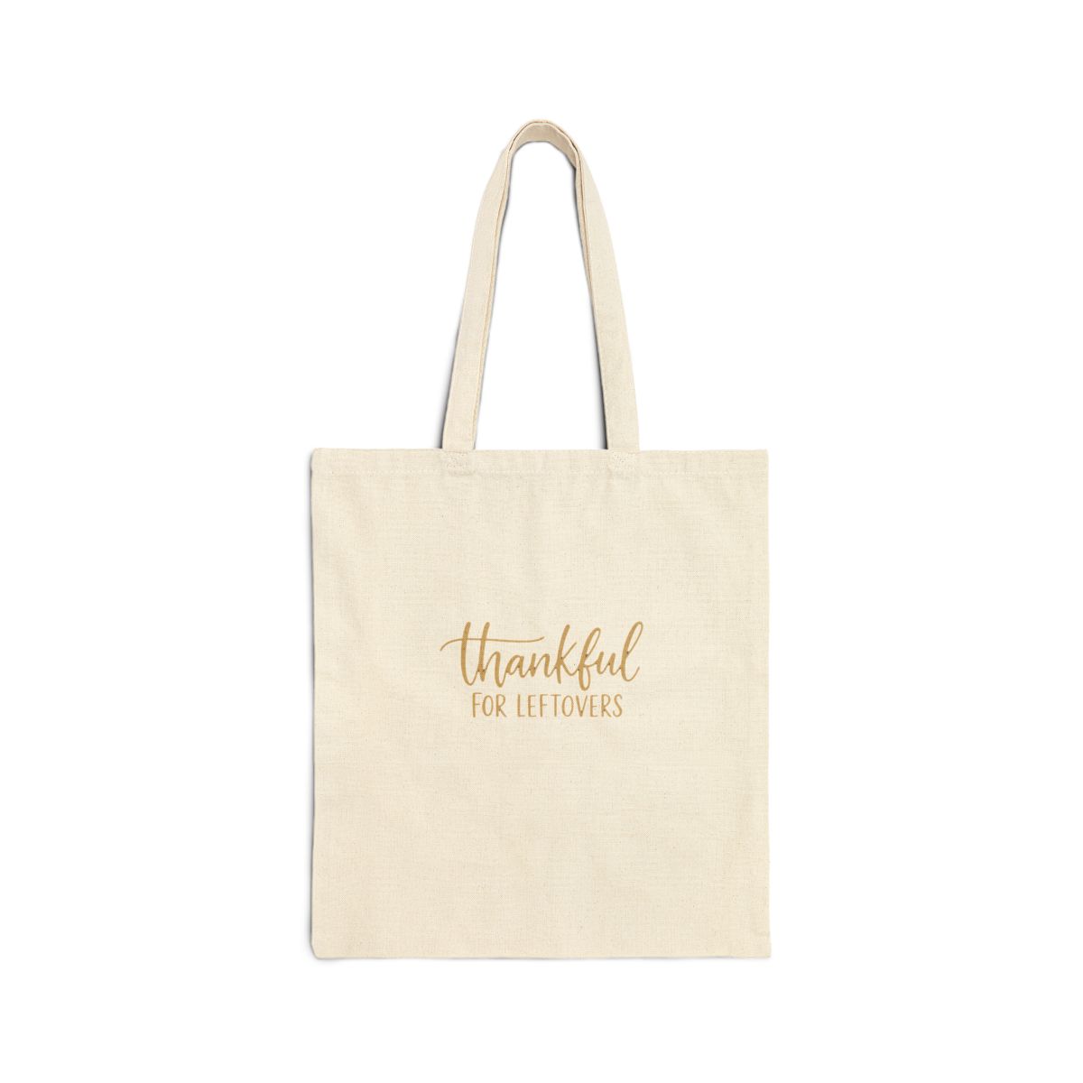 Orange canvas tote bag with gold lettering that says "thankful for leftovers". The bag is hanging on a wooden wall. - Official hats merchandise